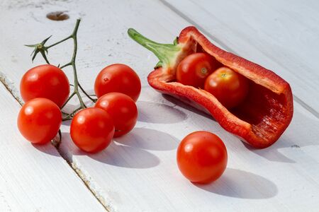 Fresh tomatoes and peppers on a board in the gardenの写真素材