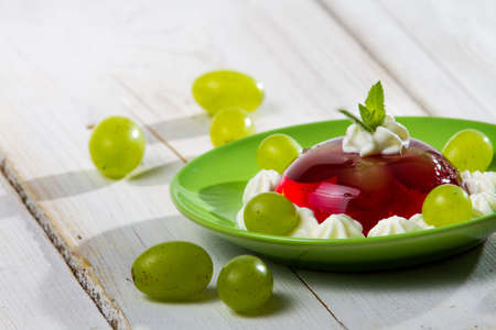Red jelly and grapes served on a plateの写真素材
