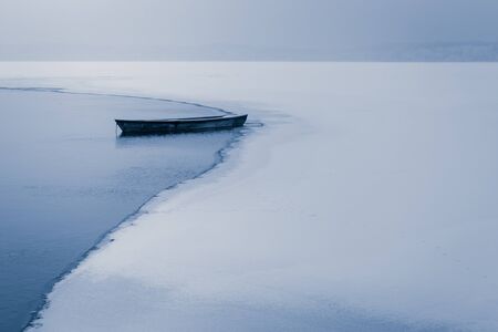 Alone boat on frozen lake in winterの写真素材