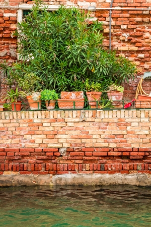 Old red brick wall along a canal in Veniceの写真素材