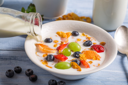 Pouring milk on cornflakes with fruitsの写真素材