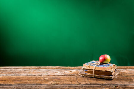 Stack of books and an apple in a classroomの写真素材
