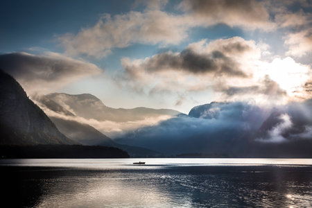 Small boat on foggy lake in the mountainsの写真素材