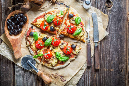Cutting homemade pizza on old tableの写真素材