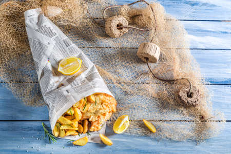 Hot fish cod with chips served in paper with lemonの写真素材