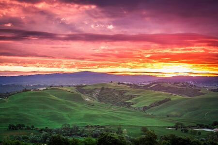 Beautiful view of green fields and meadows at sunset in Tuscany, Italyの写真素材