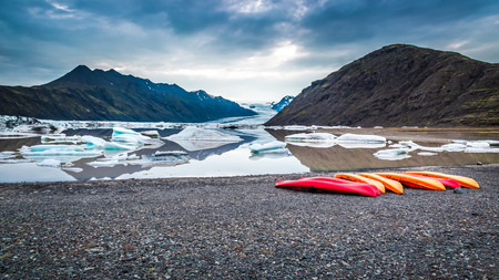 Canoes at cold glacial lake in the mountains, Icelandの写真素材