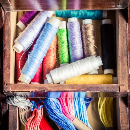 Closeup of tailor's wooden box with threads, needles and buttonsの写真素材
