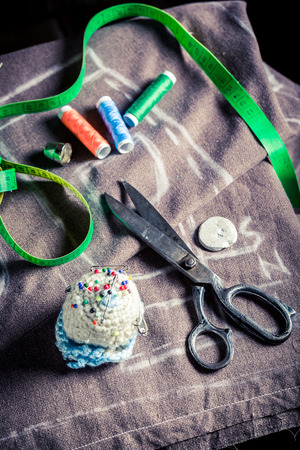 Closeup of sewing table with threads, scissors and clothの写真素材