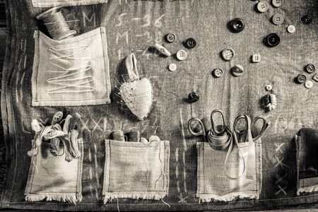 Old sewing cloth with scissors, needles and threads in tailor workshop