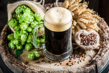 Cold dark beer with big foam, wheat and hopsの写真素材