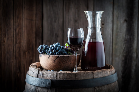 Red wine with fresh grapes on wooden background