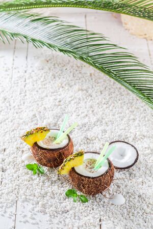 Tropical pinacolada in coconut on sandy beachの写真素材