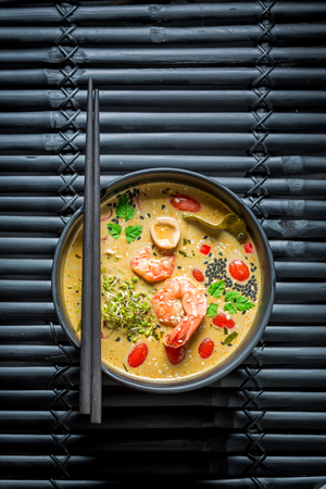 Tom Yum soup with chopsticks on black rockの写真素材