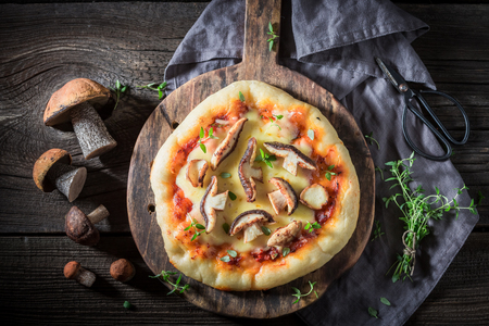 Ready to eat rustic pizza with noble mushrooms and thymeの写真素材