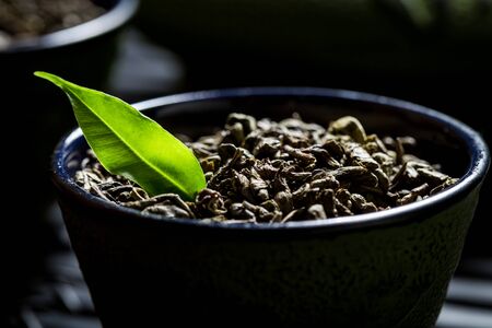 Closeup of grains green tea on black teacupの写真素材
