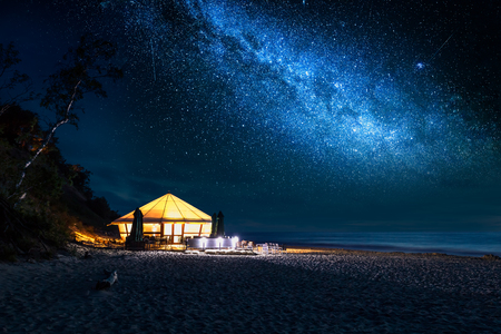 Beach with glowing tent at night with starsの写真素材