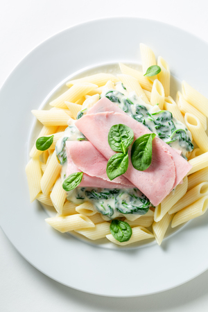 Tasty penne with bechamel sauce, ham and spinachの写真素材