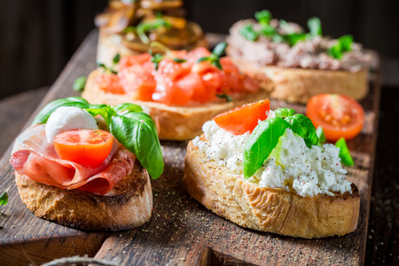 Delicious and tasty mix of bruschetta on old wooden tableの写真素材