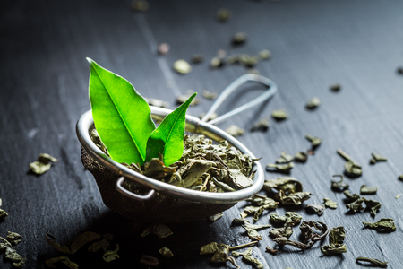 Delicious and fresh green tea in old metal strainerの写真素材