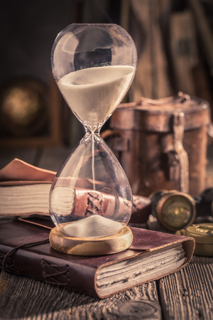 Aged hourglass and journal as a concept of journey diaryの写真素材