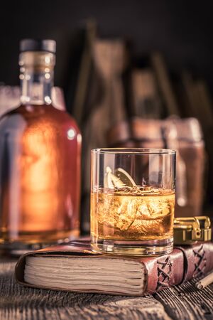 Glass of cognac with golden bottle and cold iceの写真素材