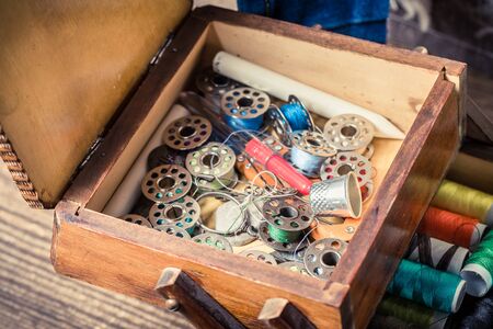 Closeup of tailor's wooden box with colorful threads and needles