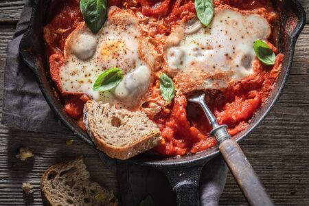 Delicious shakshuka with tomatoes, eggs and herbsの写真素材