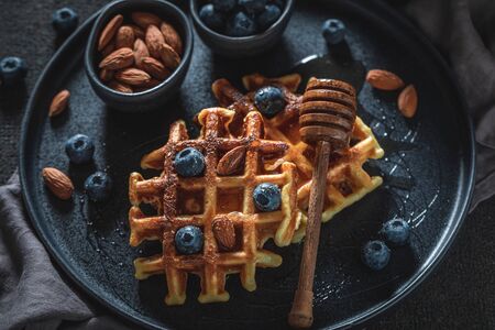 Delicious waffles with honey, almond and blueberriesの写真素材