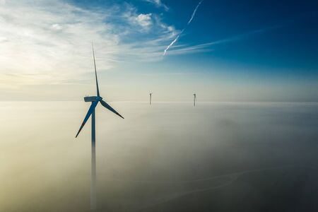 Wind turbines over mist at sunrise in Polandの写真素材