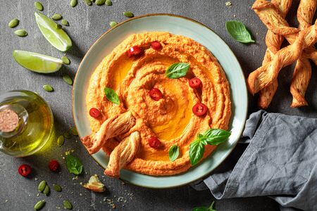 Vegan tomato hummus with olives, basil and breadsticksの写真素材
