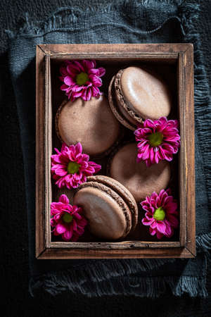Sweet chocolate macaroons in wooden box with flowersの写真素材