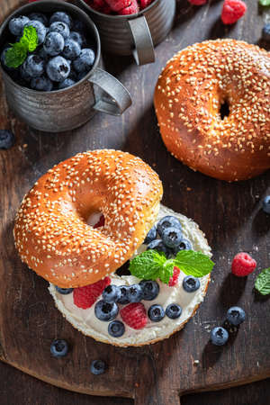 Sweet bagel with raspberries and blueberries for quick lunchの写真素材