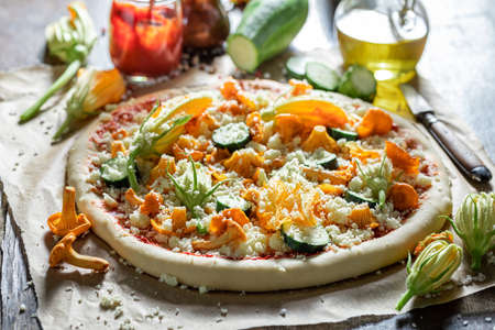 Preparations for rustic pizza with chanterelles, zucchini and mozzarella on baking paperの写真素材