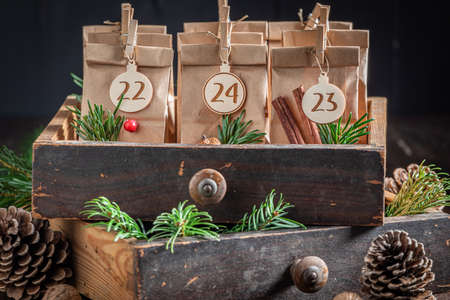 Original Christmas Advent Calendar decorated with spruce and pine cones on wooden tableの写真素材