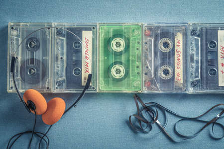 Several old audio cassettes with orange headphones on blue sofaの写真素材