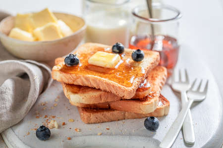 Delicious french toast with blueberries, butter and maple syrup on white tableの写真素材