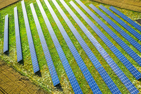 Aerial view of blue solar panels on green field, Poland