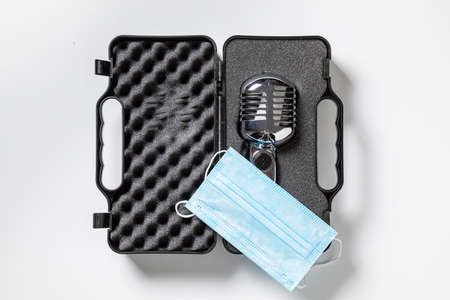 Concert and artist restriction in pandemic. Microphone and disposable mask on white background