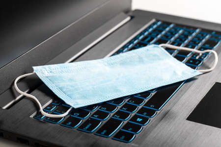 Protective mask on the laptop keyboard. Office work from home in a pandemic.