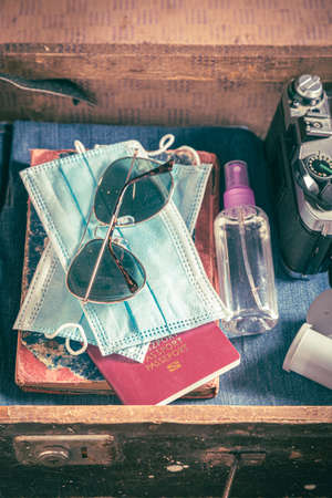Disposable mask and full suitcase as travel restrictions. Pandemic limitation. Trip preparation.の写真素材