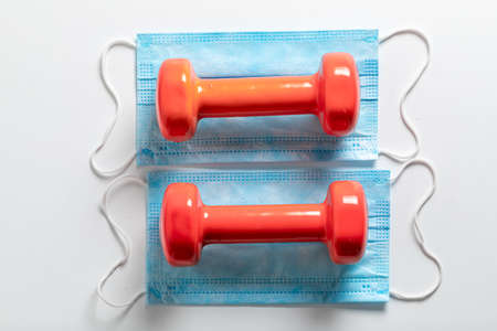 Gym in coronavirus restriction. Dumbbells and blue mask on white backgroundの写真素材