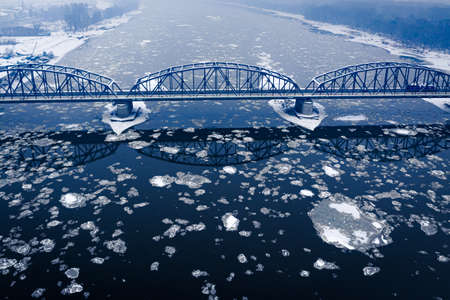 River with floe and snowy bridge in winter, aerial view of Polandの写真素材