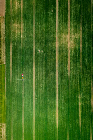 Tractor spraying the chemicals on green field, aerial view. Agriculture in Poland, Europe