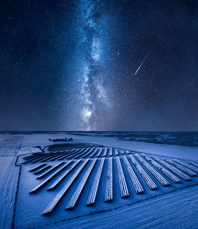 Milky way over frozen photovoltaic farm in winter. Alternative energy. Aerial view