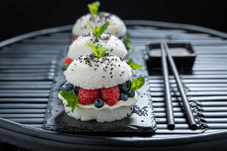 Exquisite sush burger with berries and sesame sprinkled with sesame. Japanese cuisine.