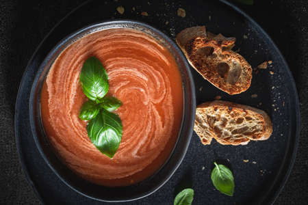 Red tomato soup in blue pottery. Homemade tomato soup with basil and toasts.の写真素材