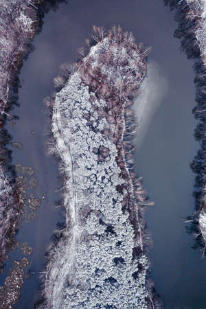 Frozen forest and cold river in winter. Aerial view of wildlife in Poland, Europe