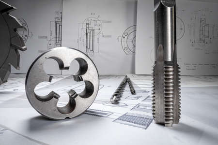 Closeup of designer desk full of drill bits, bearings and mechanical diagrams.