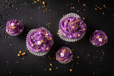 Homemade cupcakes made of sprinkles and purple whipped cream. Magnificent purple dessert with golden...